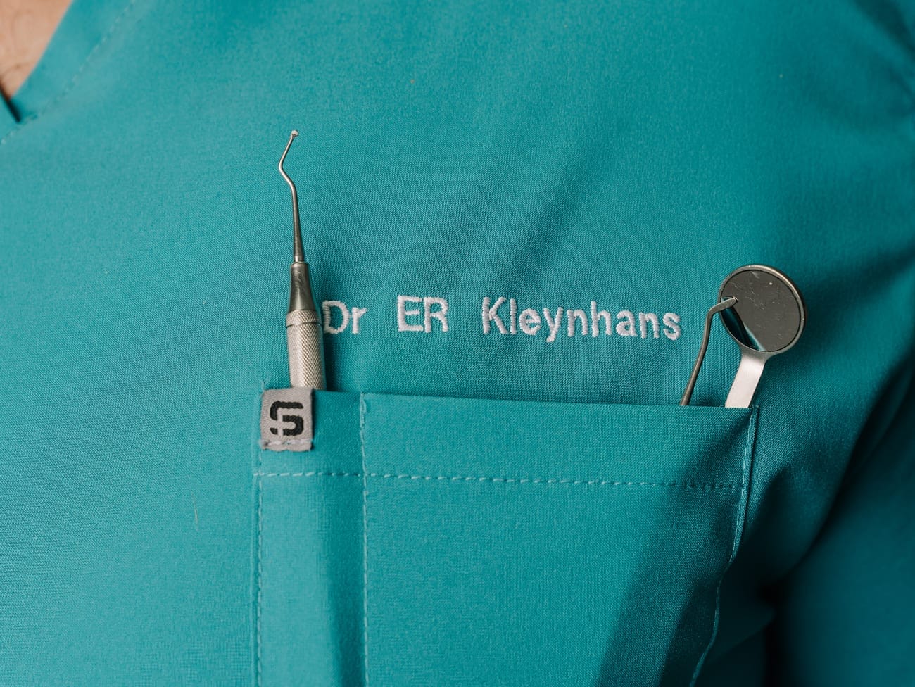 Dr ER Kleynhans's branded scrubs with dental instruments at Smile Connection Dental Studio, Pretoria