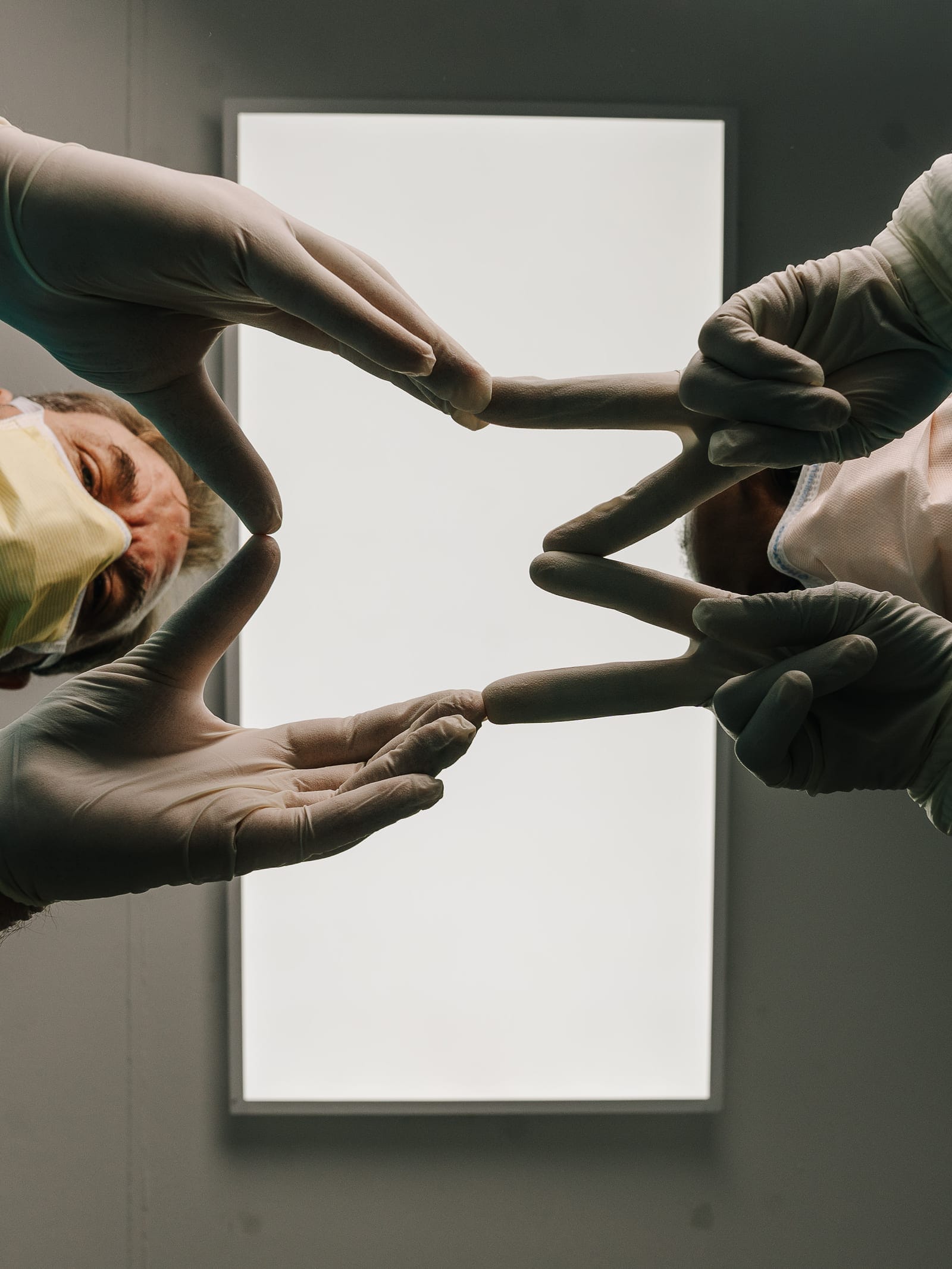 Smile Connection dentists forming the practice's tooth logo with their gloved hands over a dental light box in Newlands, Pretoria